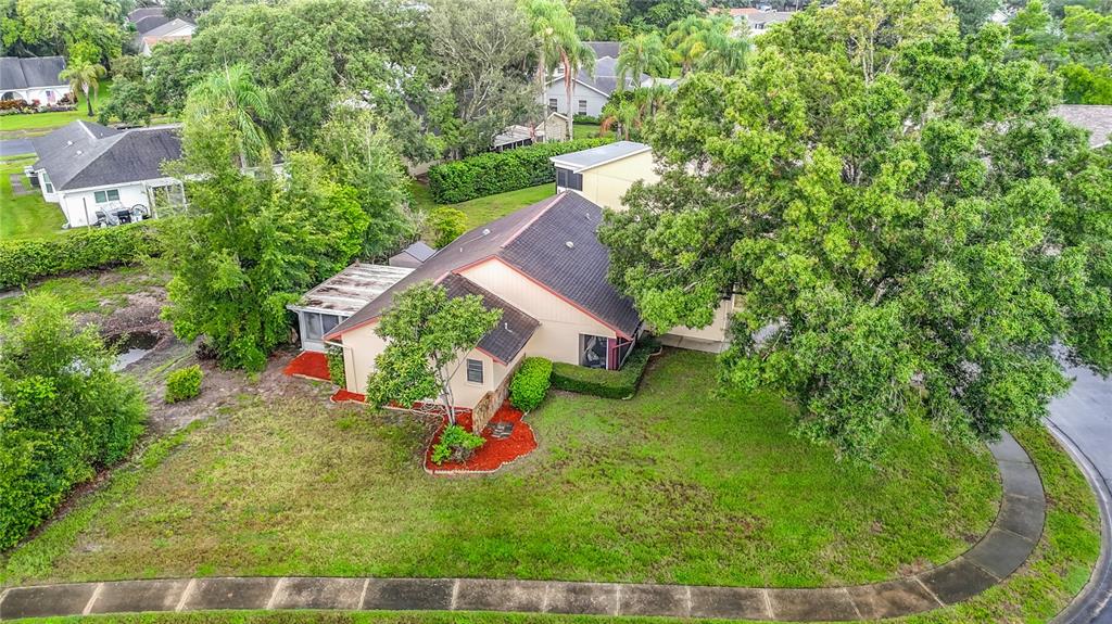 An aerial view shows a single-story house with a dark roof and a large tree — 7407 BALTUSROL DRIVE, NEW PORT RICHEY, FL