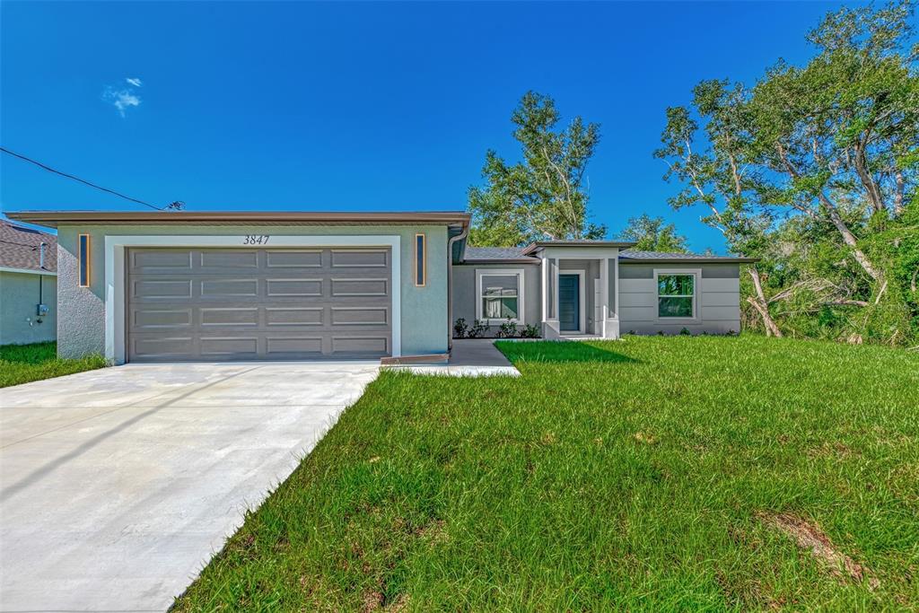 A single-story house with a gray garage, light blue stucco, and a front entrance walkway — 3847 E PRICE BOULEVARD, NORTH PORT, FL