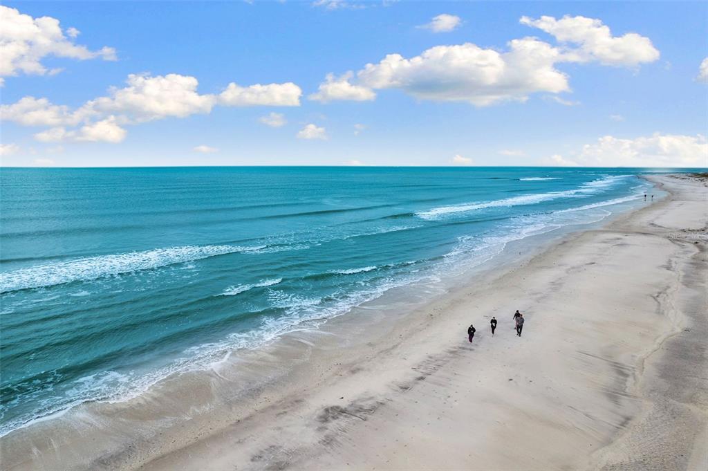 An aerial view of a sandy beach with turquoise ocean waves and people walking along — 7070 PLACIDA ROAD UNIT 1212, PLACIDA, FL