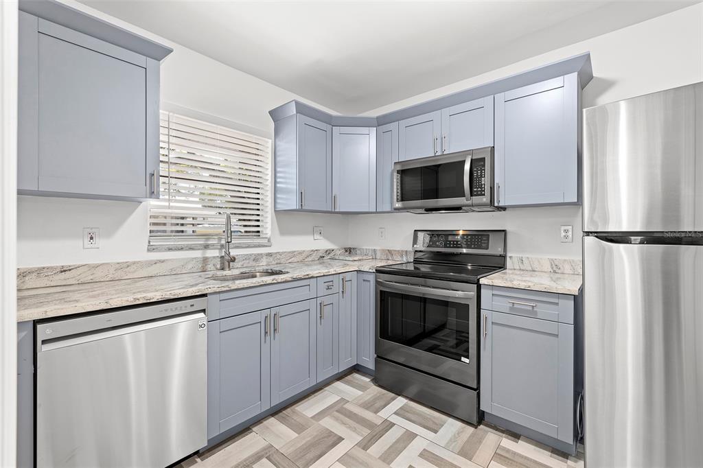 A kitchen with light blue cabinets, stainless steel appliances, and patterned tile flooring — 2539 W UNION STREET, TAMPA, FL