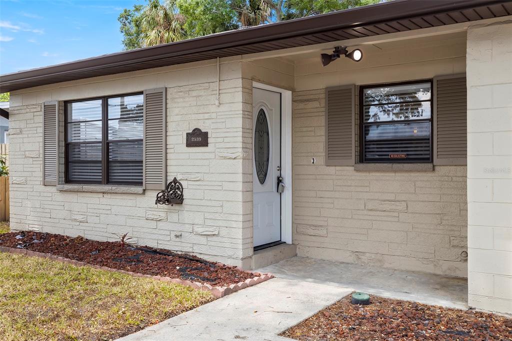 The exterior of a single-story house features light-colored stone siding, a white door, and shutters — 2539 W UNION STREET, TAMPA, FL