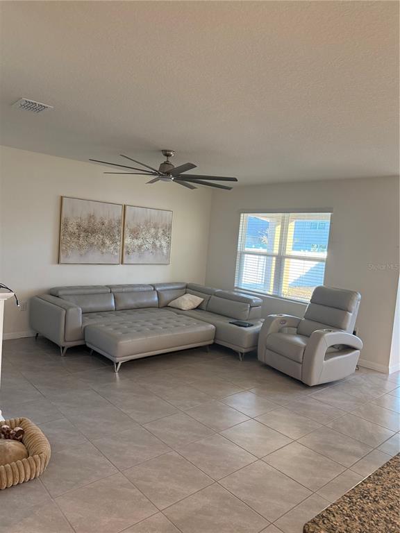 A living room features a large gray sectional sofa, a matching recliner, and tile flooring — 2541 HARMONIA HAMMOCK ROAD, ST CLOUD, FL