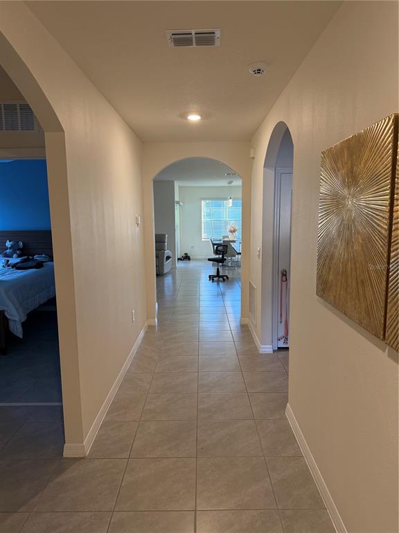 A tiled hallway leads through arched doorways toward a bright living area with a dining set — 2541 HARMONIA HAMMOCK ROAD, ST CLOUD, FL