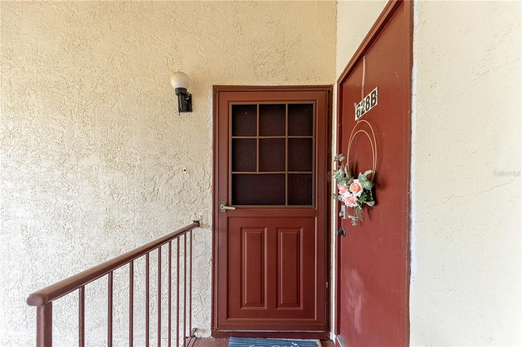 An exterior view of a brown front door with a storm door and a wreath — 628 MIDWAY DRIVE UNIT B, OCALA, FL