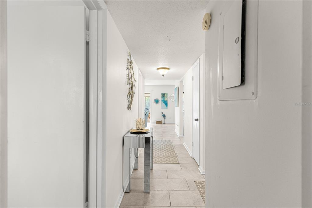 A hallway with light tile flooring leads to a living area with wall art — 628 MIDWAY DRIVE UNIT B, OCALA, FL