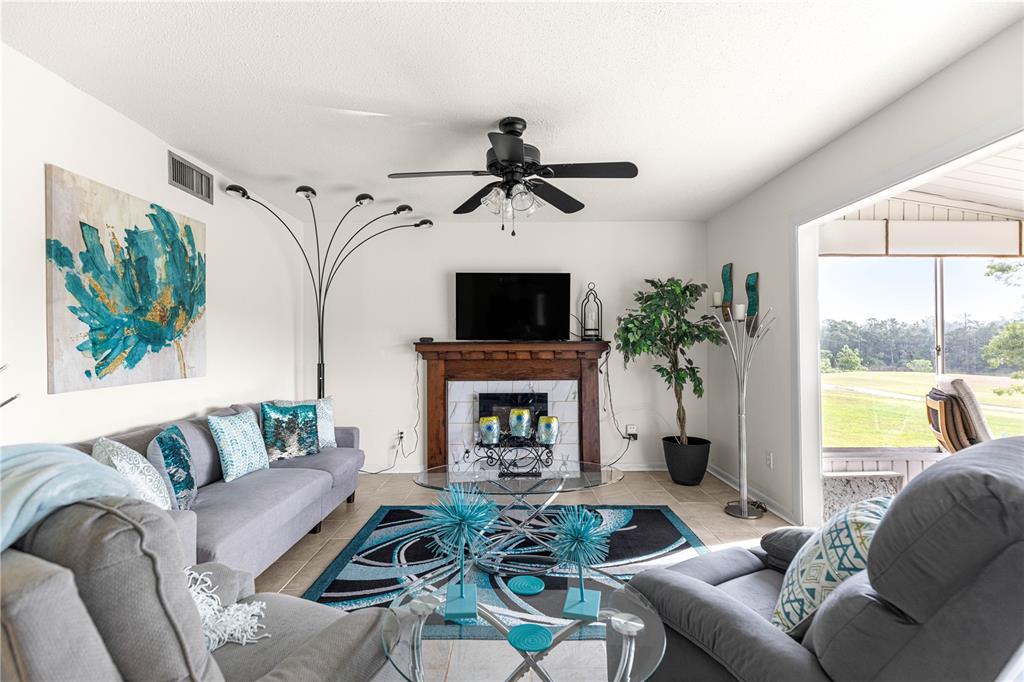 A living room features a fireplace, a television, gray sofas, and a ceiling fan — 628 MIDWAY DRIVE UNIT B, OCALA, FL
