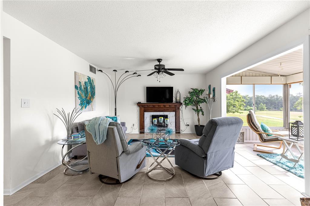 A living room features a fireplace, tile flooring, and a view of a grassy yard — 628 MIDWAY DRIVE UNIT B, OCALA, FL