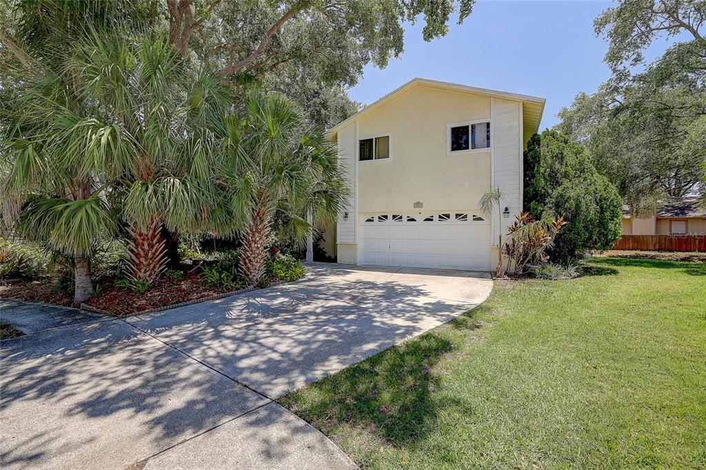 A two-story house with a light yellow exterior, a single-car garage, and surrounding palm trees — 4505 33RD AVENUE W, BRADENTON, FL