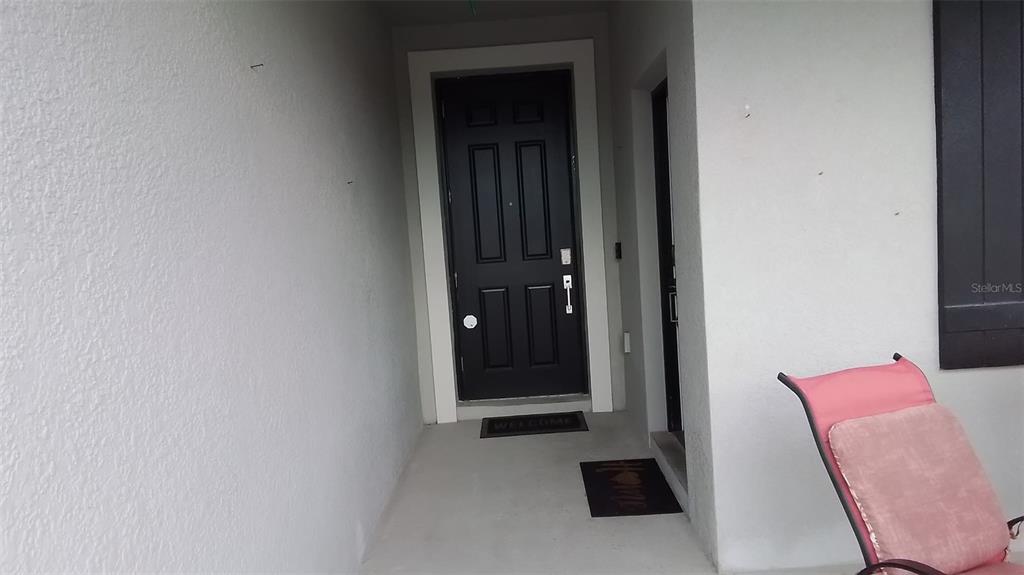 A black front door is set within a covered entryway with light-colored stucco walls — 113 TAFT DRIVE, DAVENPORT, FL