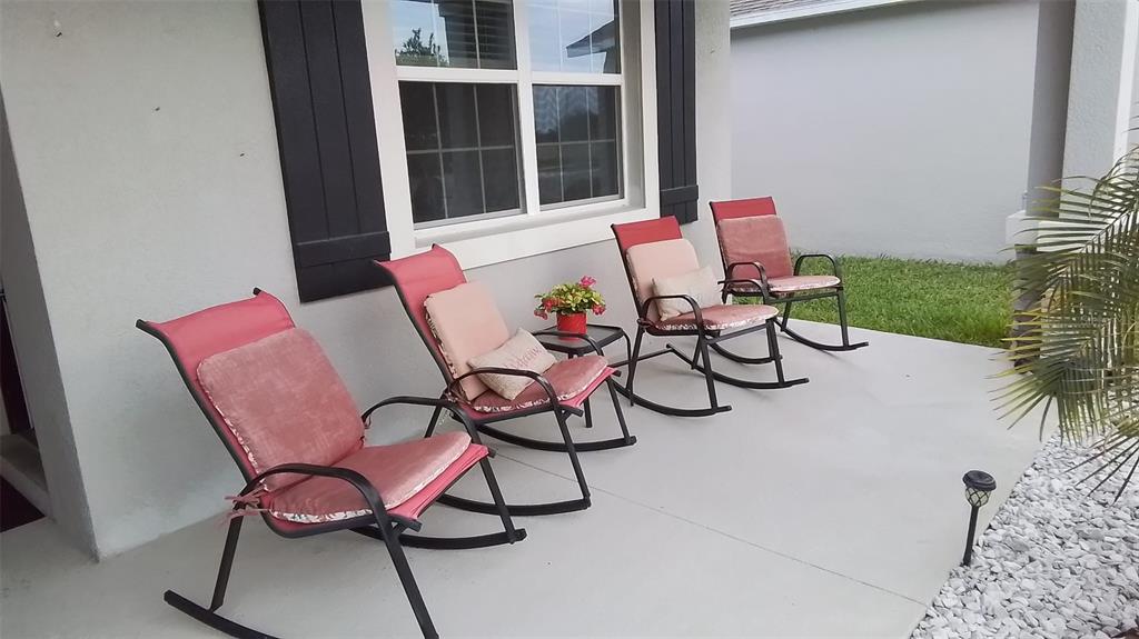 Four rocking chairs with pink cushions sit on a concrete patio outside a house — 113 TAFT DRIVE, DAVENPORT, FL