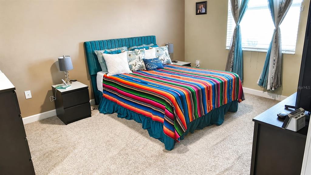 A bedroom features a teal upholstered headboard, a colorful striped blanket, and two nightstands — 113 TAFT DRIVE, DAVENPORT, FL