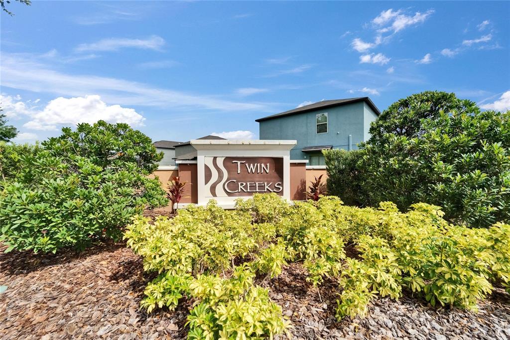 A sign for Twin Creeks stands in front of a residential building and landscaping — 10119 ROSE PETAL PLACE, RIVERVIEW, FL