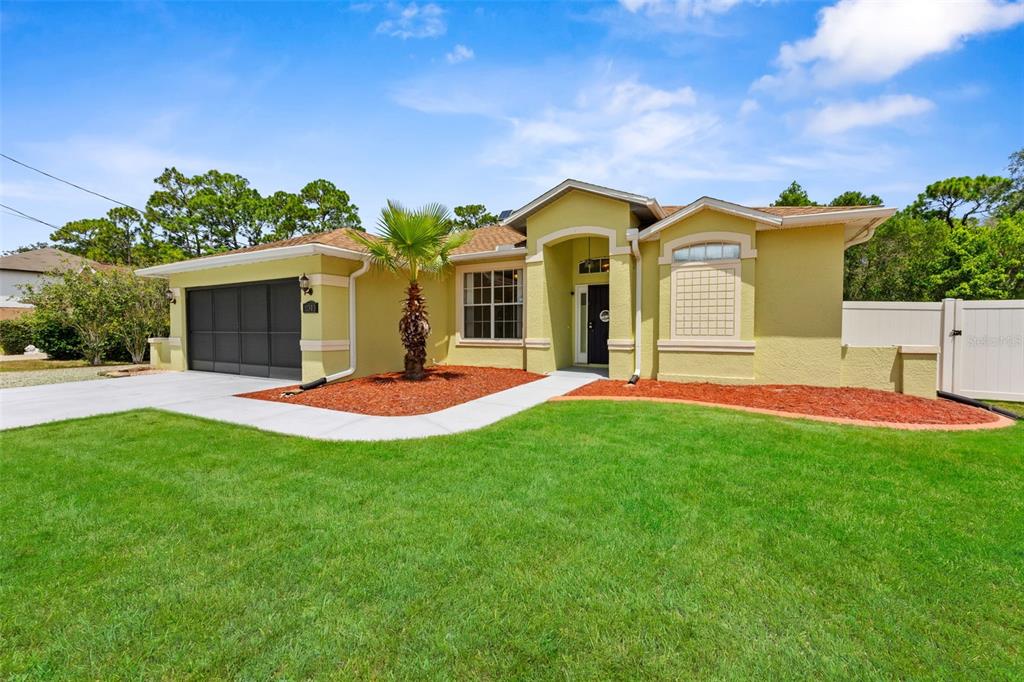 A single-story house with yellow stucco siding, a two-car garage, and a front palm tree — 11303 TOPAZ STREET, SPRING HILL, FL
