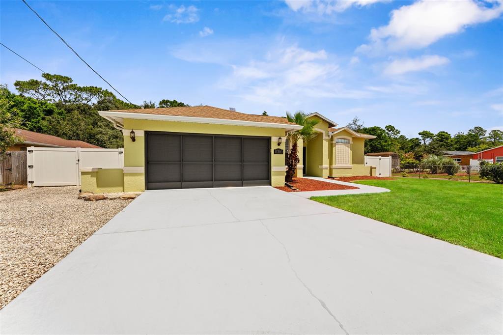 A light green house with a dark garage door and a concrete driveway — 11303 TOPAZ STREET, SPRING HILL, FL