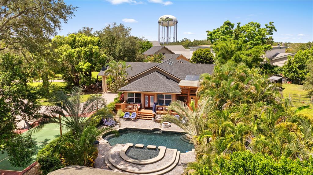 An aerial view shows a house with a swimming pool, tennis court, and water tower — 20 BOGIE LANE, PALM HARBOR, FL