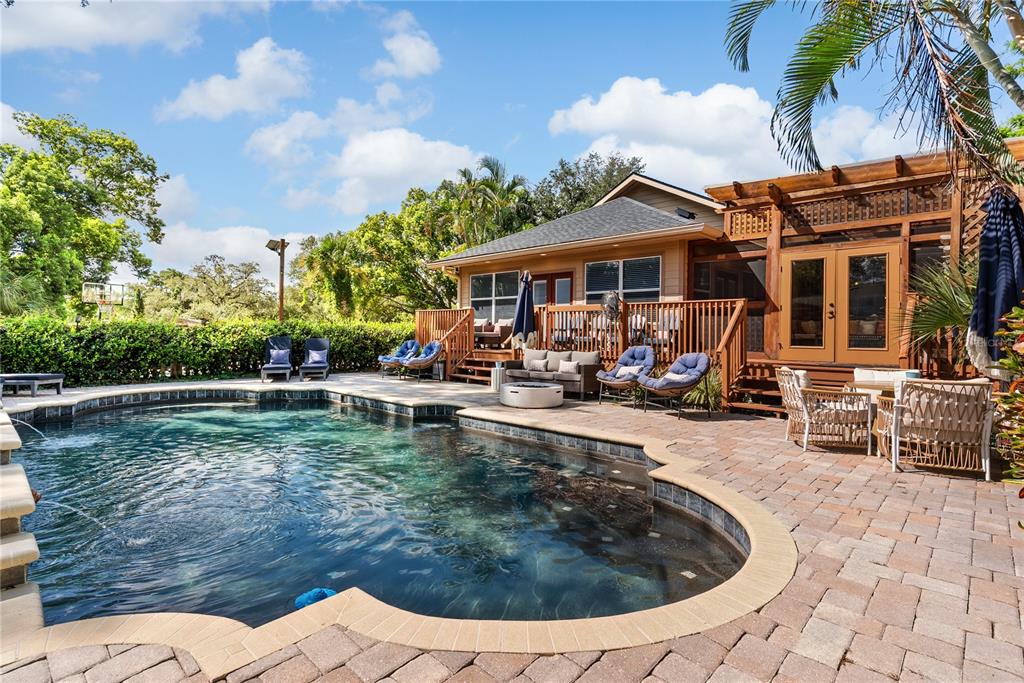 A backyard features a swimming pool with a fountain next to a wooden deck and patio — 20 BOGIE LANE, PALM HARBOR, FL