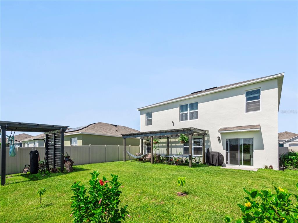 The backyard of a two-story house features a wooden pergola, a lawn, and a fence — 270 MEADOWBROOK BOULEVARD, WINTER HAVEN, FL