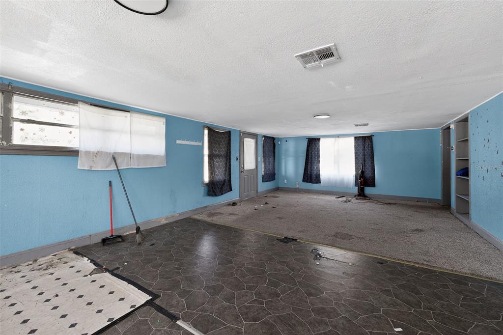A kitchen with white cabinets and stainless appliances opens into a carpeted living area — 108 EARL AVENUE, AUBURNDALE, FL