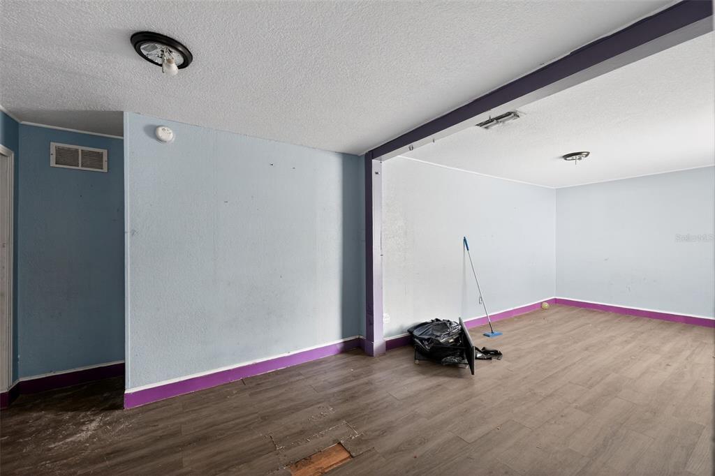 A living room with blue walls, a mix of tile and carpet flooring, and windows — 108 EARL AVENUE, AUBURNDALE, FL