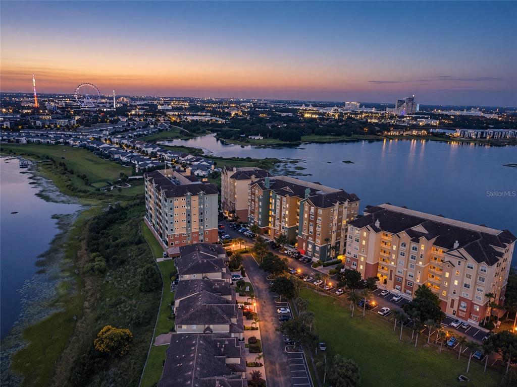 An aerial view of a multi-story apartment complex situated along a lake at sunset — 8749 THE ESPLANADE UNIT 24, ORLANDO, FL