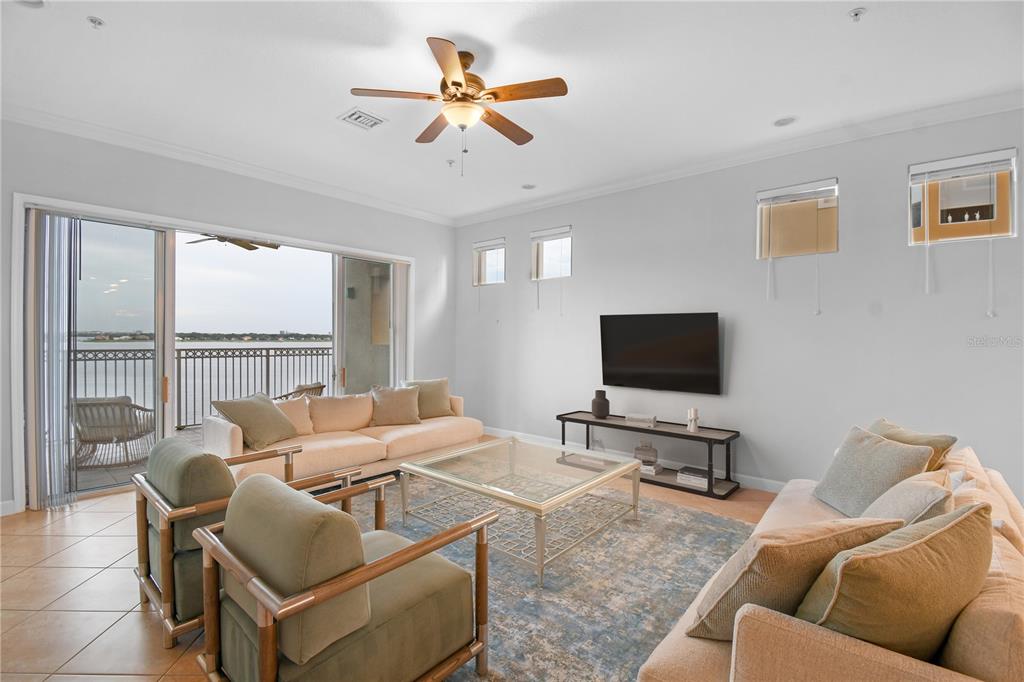 A living room features a beige sofa, two green armchairs, a glass coffee table, and balcony — 8749 THE ESPLANADE UNIT 24, ORLANDO, FL