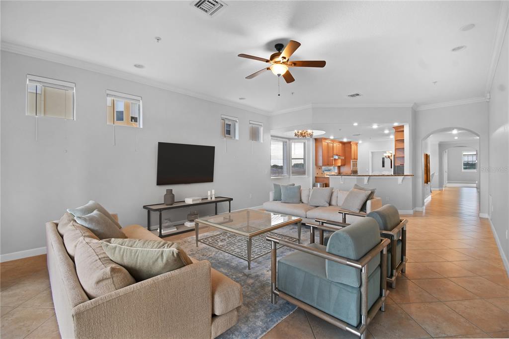 A spacious living room features a large sectional, two armchairs, and an open-concept kitchen — 8749 THE ESPLANADE UNIT 24, ORLANDO, FL