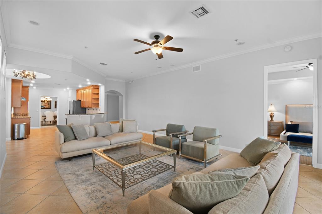 A living room with tile floors, a ceiling fan, and a glass-topped coffee table — 8749 THE ESPLANADE UNIT 24, ORLANDO, FL