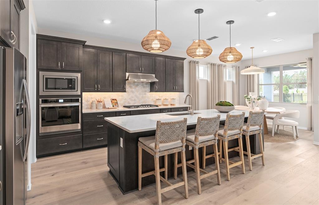 A modern kitchen features dark wood cabinets, a large white island, and four woven barstools — 5094 SUNFALLS AVENUE, ST CLOUD, FL
