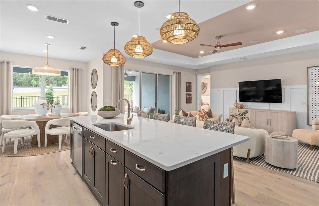 A kitchen island with a white countertop sits in an open-concept living and dining area — 5094 SUNFALLS AVENUE, ST CLOUD, FL