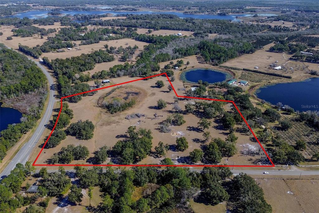 An aerial view shows a large, grassy, tree-dotted plot of land outlined in red — CARTER ROAD, DELAND, FL
