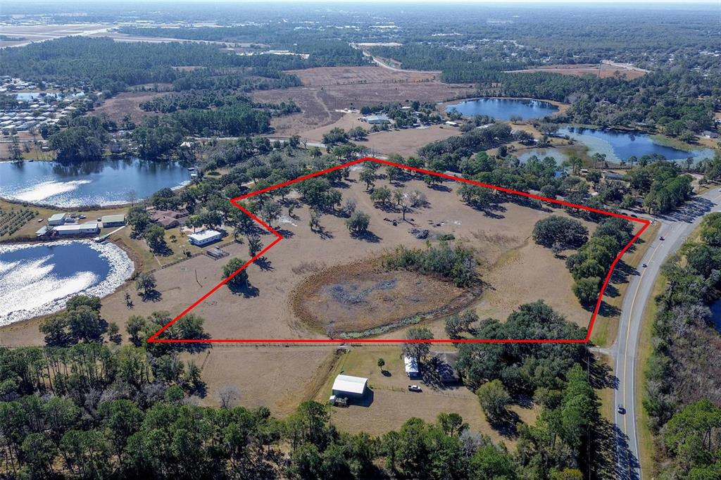 An aerial view shows a large, grassy plot of land outlined in red near water — CARTER ROAD, DELAND, FL