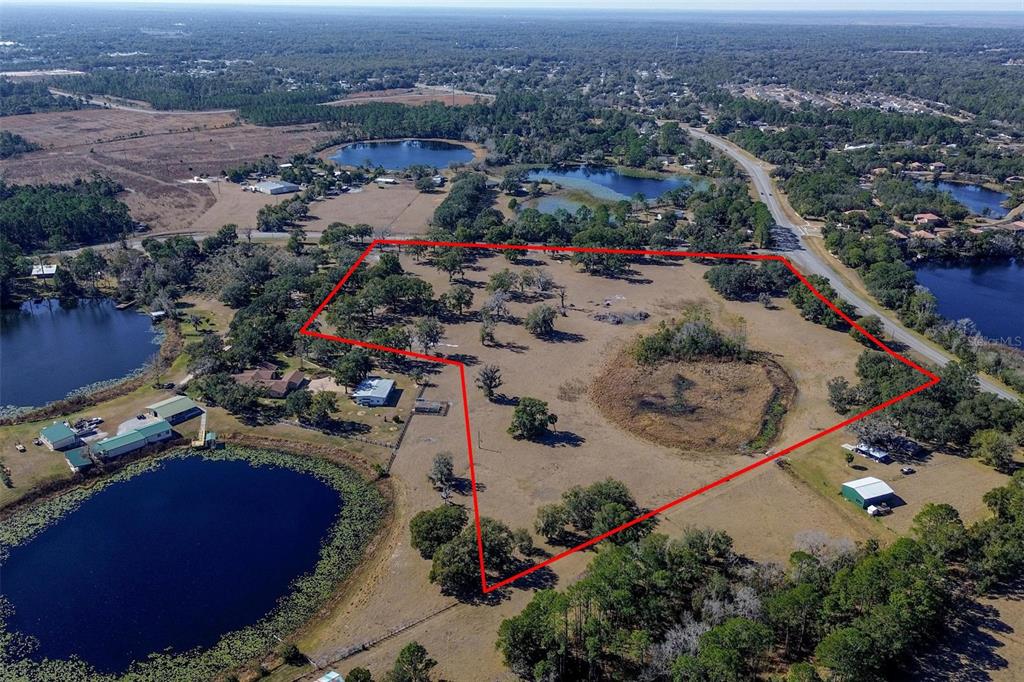 An aerial view shows a large, grassy plot of land outlined in red near lakes — CARTER ROAD, DELAND, FL