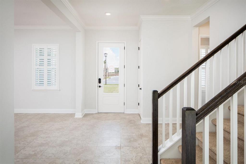 An entryway with tile flooring, a white front door, and a staircase with dark railings — 6677 WAKE STREET, ST CLOUD, FL