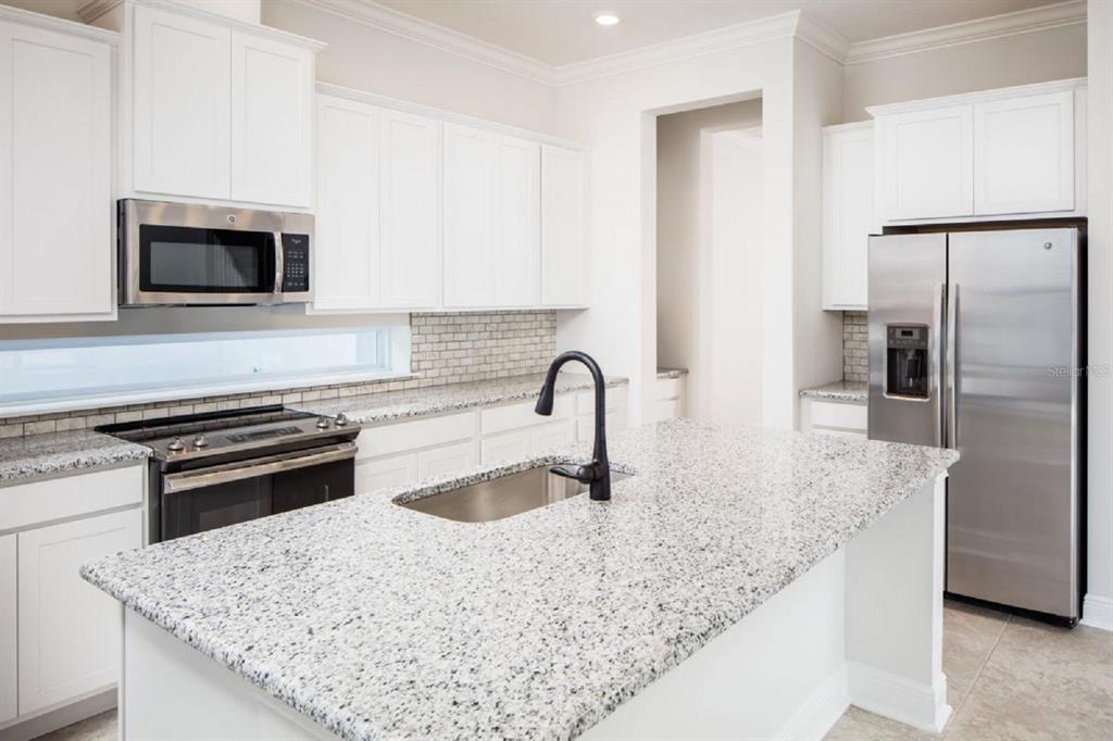 A kitchen with white cabinets, granite countertops, stainless steel appliances, and a central island — 6677 WAKE STREET, ST CLOUD, FL