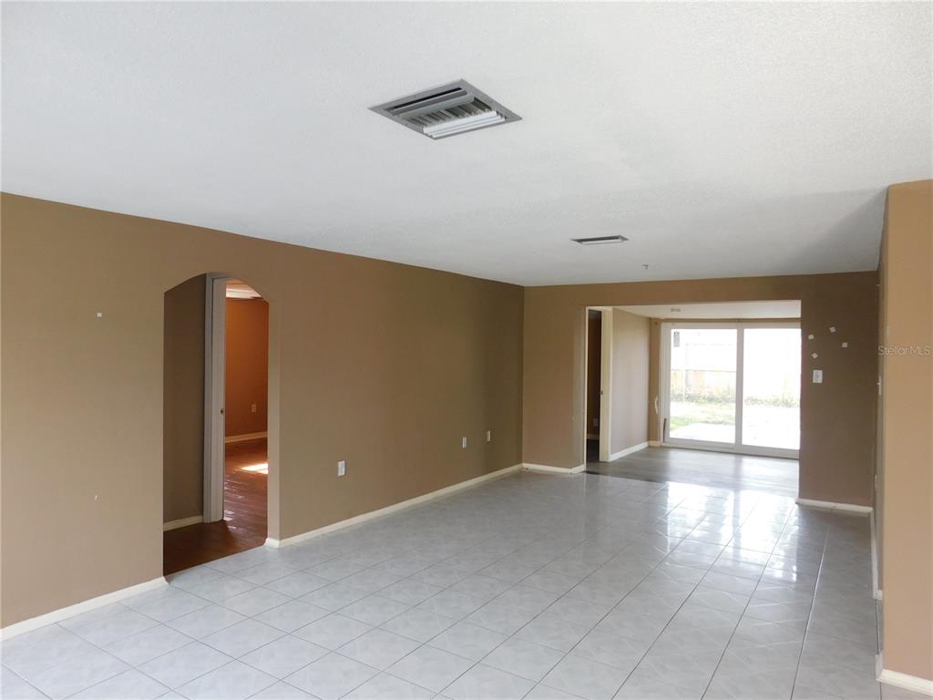 A living area with light tile flooring, tan walls, and a sliding glass door — 3220 COLDWELL DRIVE, HOLIDAY, FL