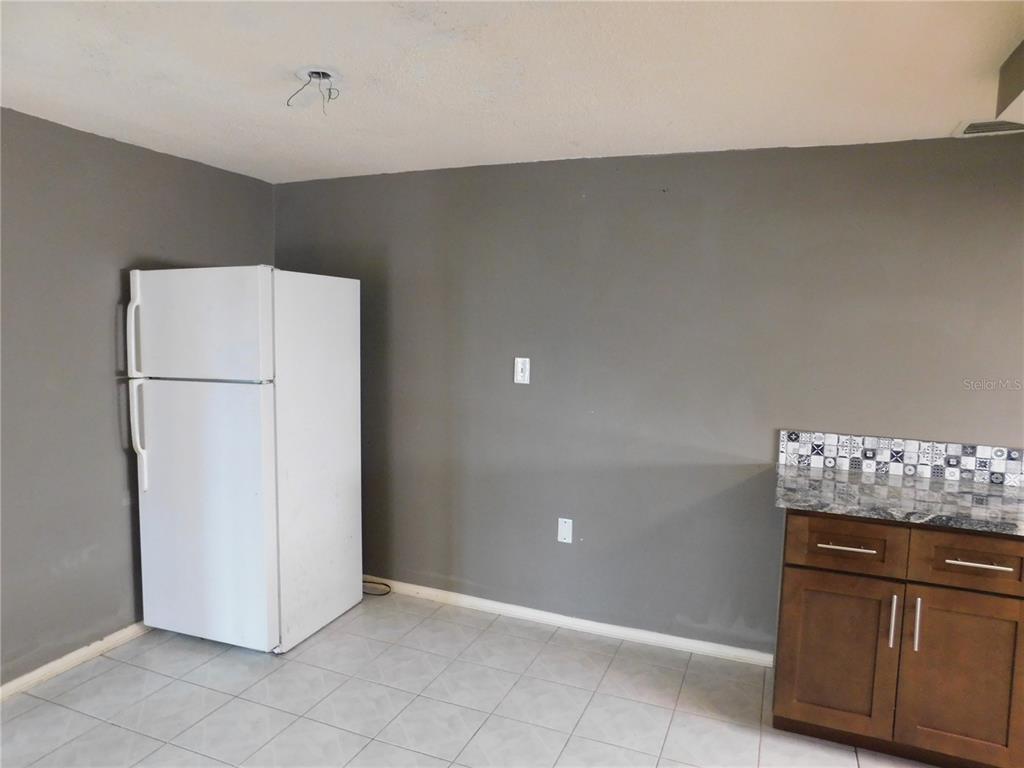 A kitchen features a white refrigerator, gray walls, tiled flooring, and dark wood cabinets — 3220 COLDWELL DRIVE, HOLIDAY, FL