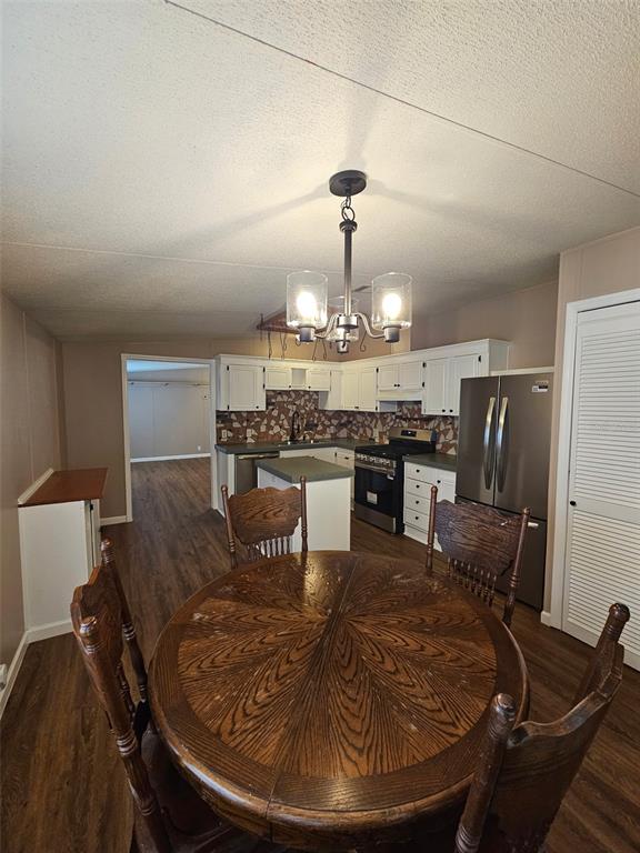 A dining area with a round wooden table leads into a kitchen with white cabinets — 5815 N TSALA APOPKA DRIVE, HERNANDO, FL