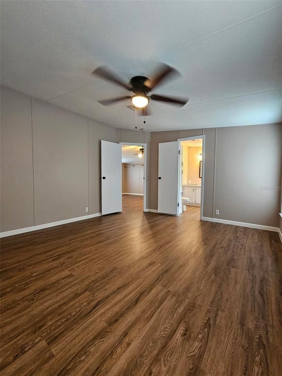 A bedroom with wood-look flooring, a ceiling fan, and two open doorways leading to other rooms — 5815 N TSALA APOPKA DRIVE, HERNANDO, FL