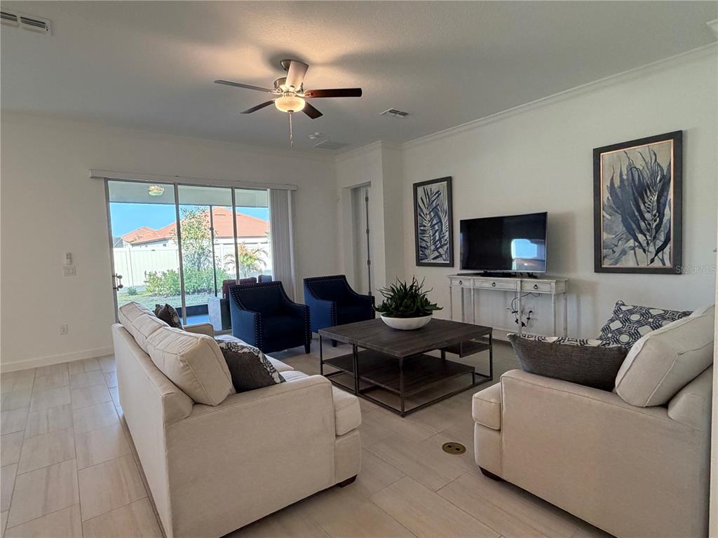 A living room features light tile floors, two sofas, two blue armchairs, and a television — 17165 SCUBA CREST STREET, WIMAUMA, FL