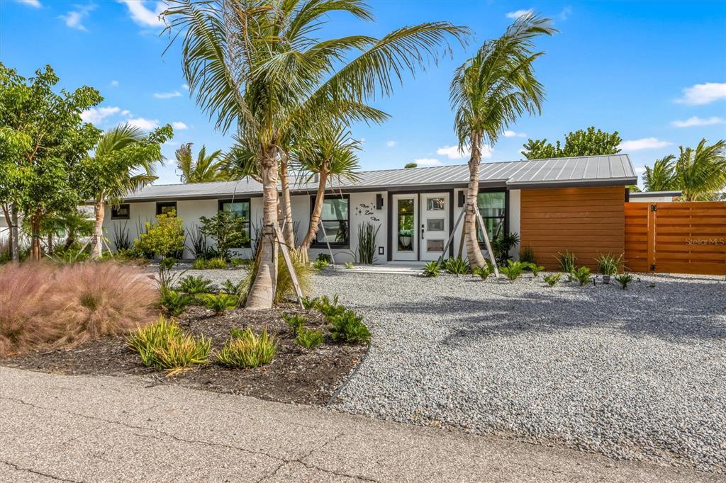 A single-story house with a metal roof, white exterior, and a gravel front yard — 505 65TH STREET, HOLMES BEACH, FL
