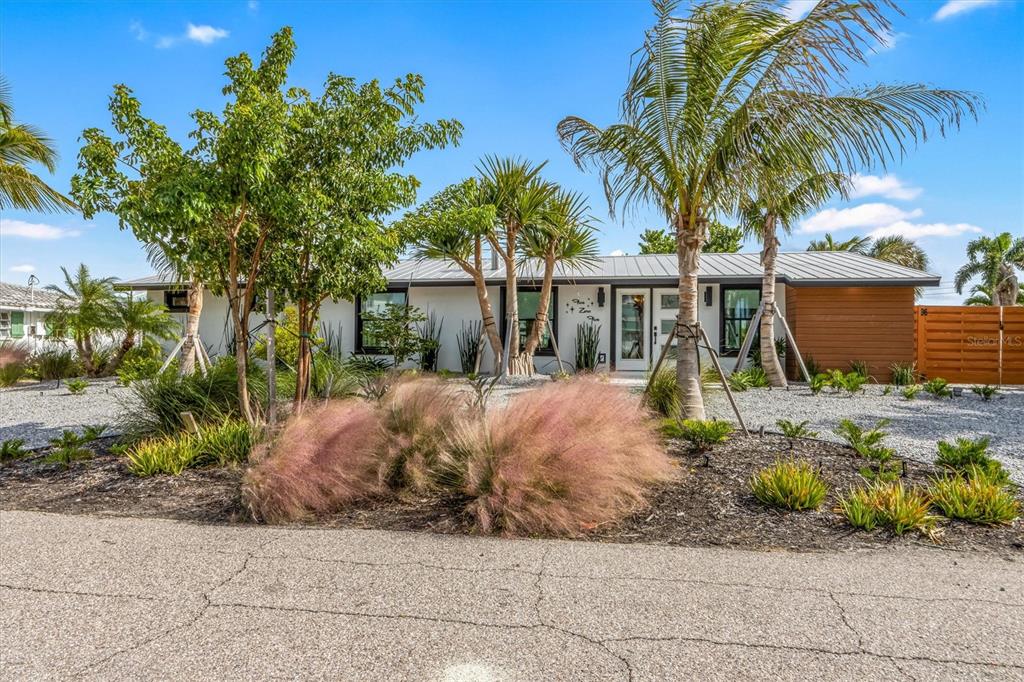 A single-story house with a white exterior, metal roof, and palm trees in the yard — 505 65TH STREET, HOLMES BEACH, FL