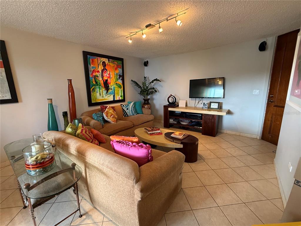 A living room features two tan sofas, a coffee table, and a wall-mounted television — 155 CARRAZO UNIT 8D, GUAYNABO, PR