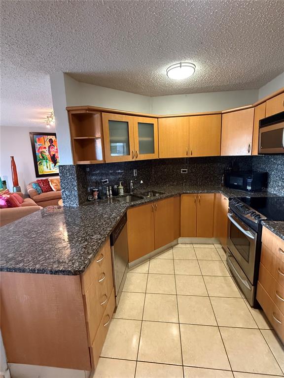 A kitchen features light wood cabinets, dark granite countertops, and stainless steel appliances — 155 CARRAZO UNIT 8D, GUAYNABO, PR