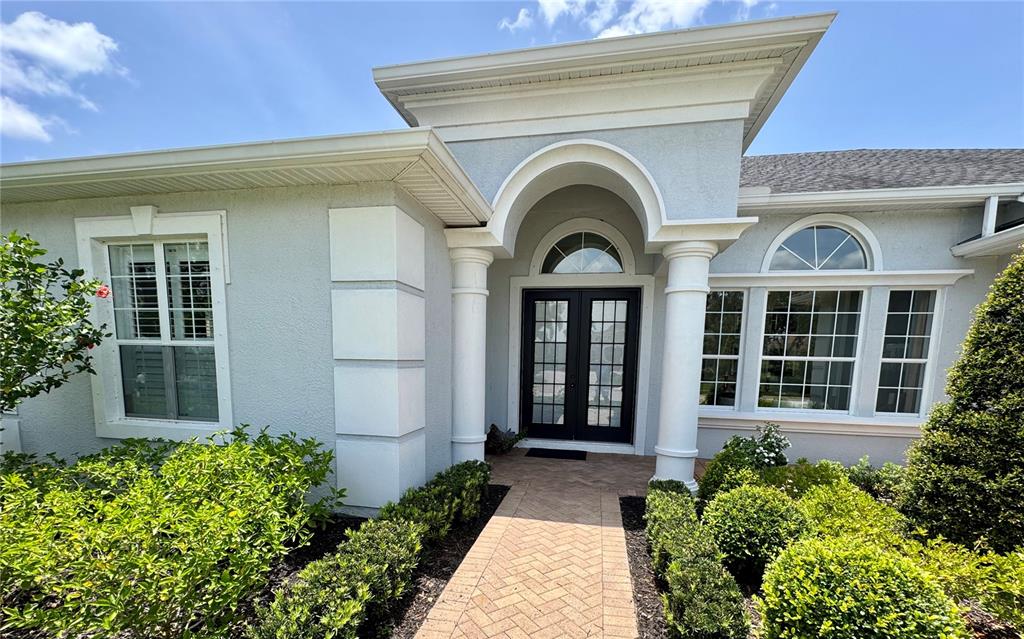 The exterior of a house features a double-door entrance with columns and a paved walkway — 1539 ORMOND TERRACE, PARRISH, FL