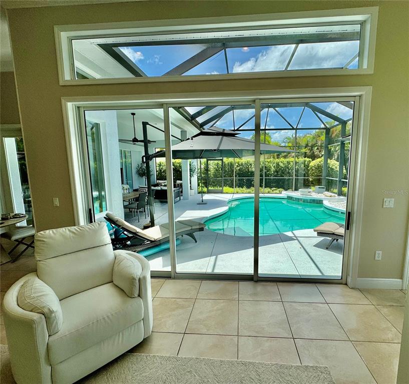 A living area with a white armchair overlooks a screened-in pool and patio — 1539 ORMOND TERRACE, PARRISH, FL