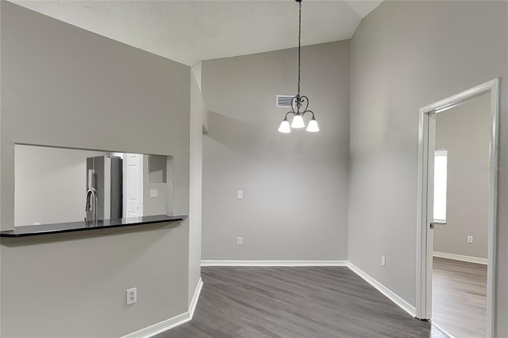 A dining area with gray walls, wood-look flooring, a chandelier, and a kitchen pass-through window — 1718 BRANDON TRACE AVENUE, BRANDON, FL