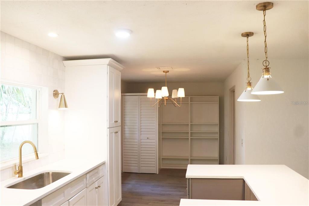 A kitchen features white cabinetry, a sink, pendant lighting, and an adjacent pantry area — 1604 STARFIRE LANE, OCOEE, FL