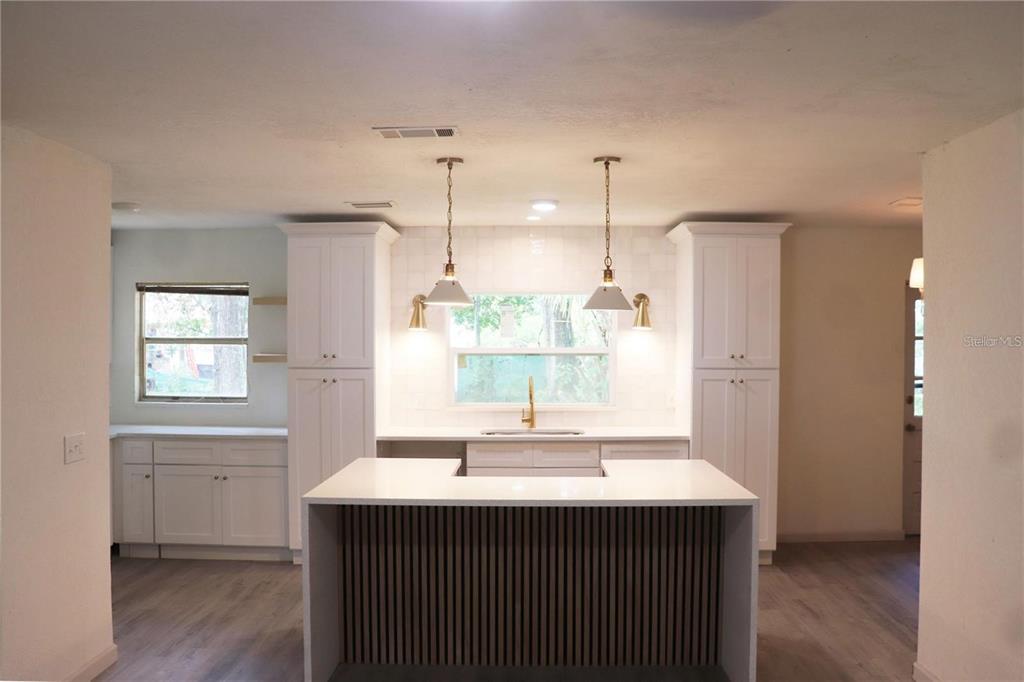 A kitchen features white cabinets, a central island with slatted wood, and two pendant lights — 1604 STARFIRE LANE, OCOEE, FL