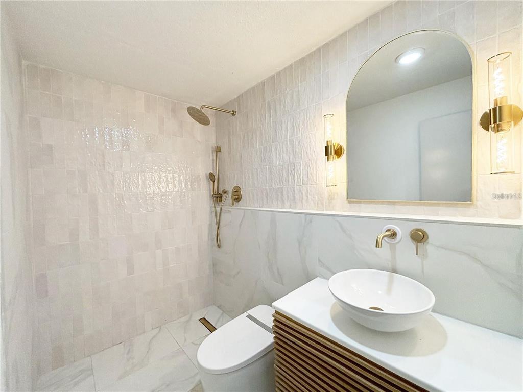 A modern bathroom features a walk-in shower, a vessel sink vanity, and gold-toned fixtures — 1604 STARFIRE LANE, OCOEE, FL
