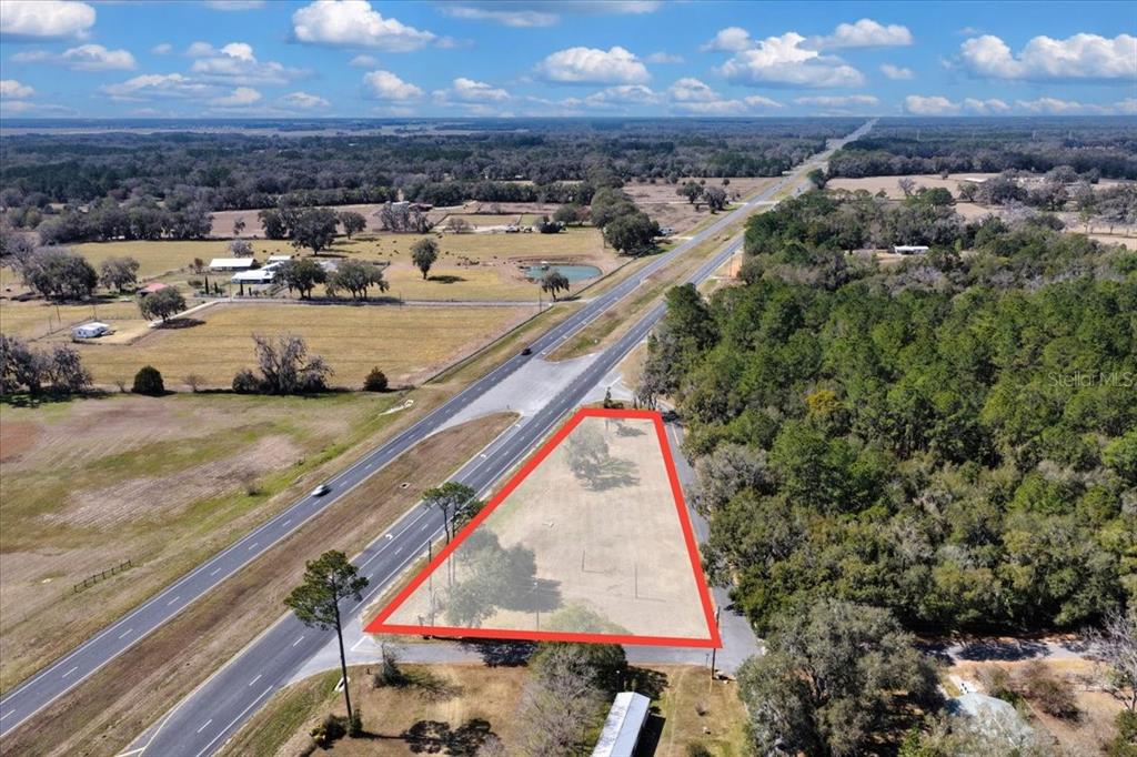 An aerial view shows a triangular vacant lot outlined in red beside a highway — 18450 NE 40TH STREET, WILLISTON, FL